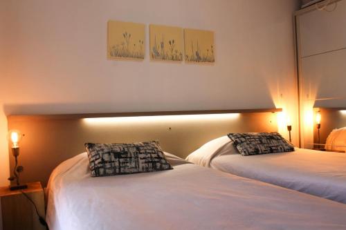 a hotel room with two beds and two lamps at Departamentos Fleming, luminosos p hasta 4 personas in Paraná
