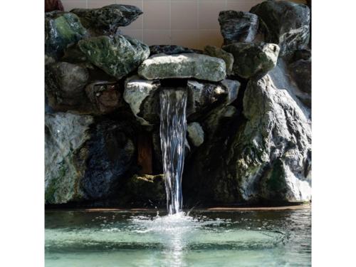 a waterfall in a pool of water with rocks at Takamine Kogen Hotel - Vacation STAY 36239v in Shin-kazawa