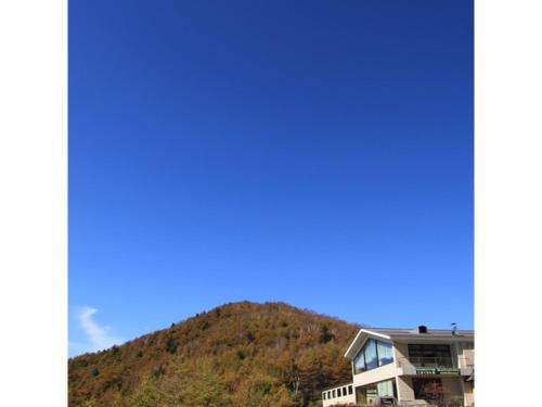a house with a mountain in the background at Takamine Kogen Hotel - Vacation STAY 36239v in Shin-kazawa