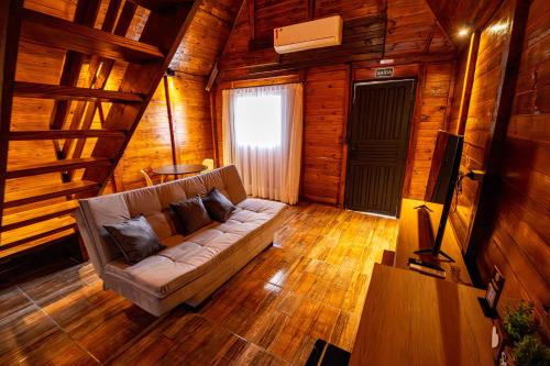a living room with a couch in a wooden cabin at Chácara Cabanas e Eventos Peniel in Campina Grande do Sul