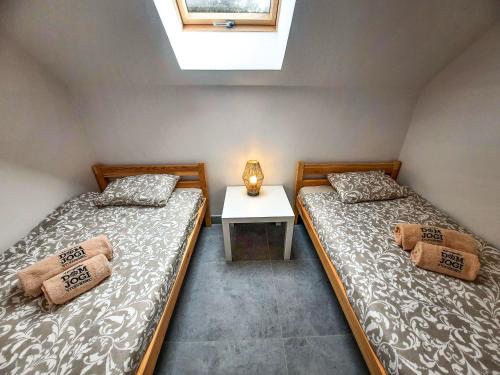 two twin beds in a room with a window at Dom Jogi Studzieniec in Studzieniec