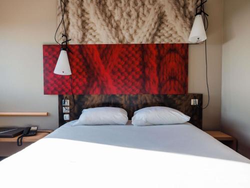 a bedroom with a large bed with two white pillows at ibis Valence Sud in Valence