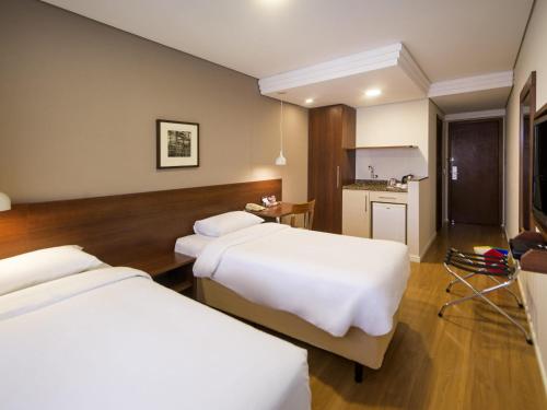 a hotel room with two beds and a kitchen at Mercure Curitiba Golden in Curitiba