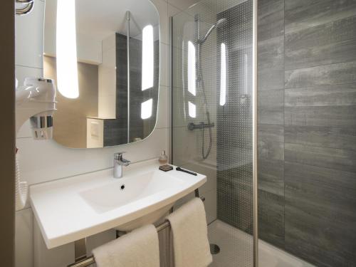 a bathroom with a sink and a shower with a mirror at ibis Tilburg in Tilburg