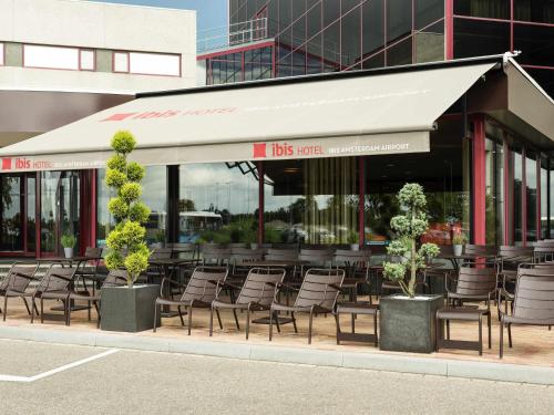 a restaurant with chairs and tables and a building at Ibis Schiphol Amsterdam Airport in Badhoevedorp