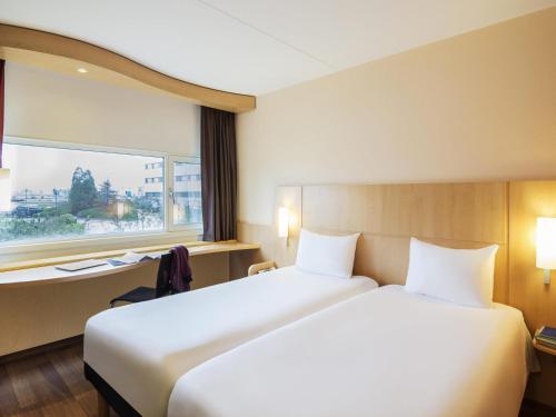 a hotel room with a large bed and a window at Ibis Schiphol Amsterdam Airport in Badhoevedorp