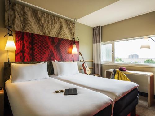 a hotel room with a large bed and a window at Ibis Schiphol Amsterdam Airport in Badhoevedorp