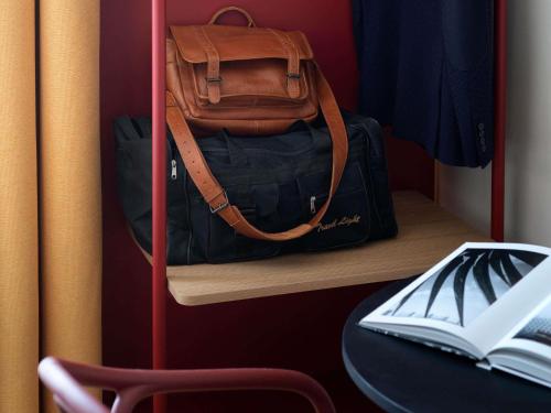 a bag sitting on a shelf with a book at ibis Styles Dijon Central in Dijon
