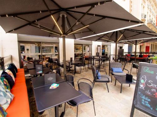 a restaurant with tables and chairs under large umbrellas at ibis Styles Dijon Central in Dijon
