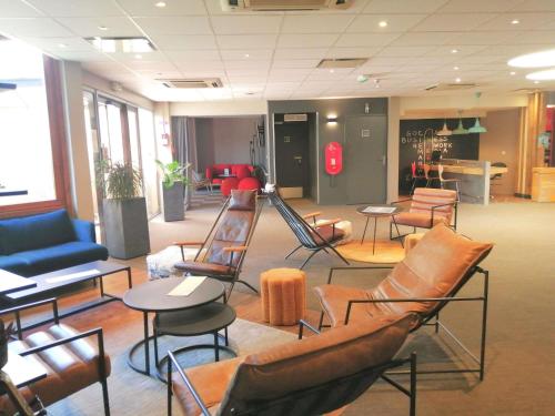 a waiting room with chairs and tables in a building at ibis Poitiers Sud in Poitiers