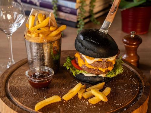 a hamburger and french fries on a plate with a glass at ibis Poitiers Sud in Poitiers