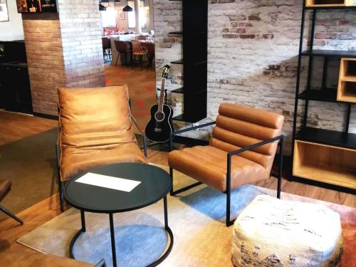 a living room with a couch and a table and a guitar at ibis Poitiers Sud in Poitiers