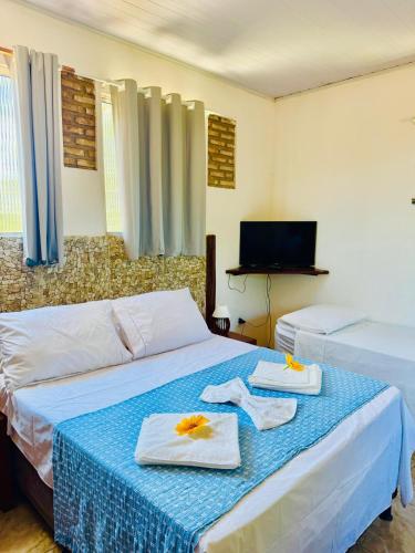 - une chambre avec 2 lits, des serviettes et une télévision dans l'établissement Residencial Adriê, à Itacaré