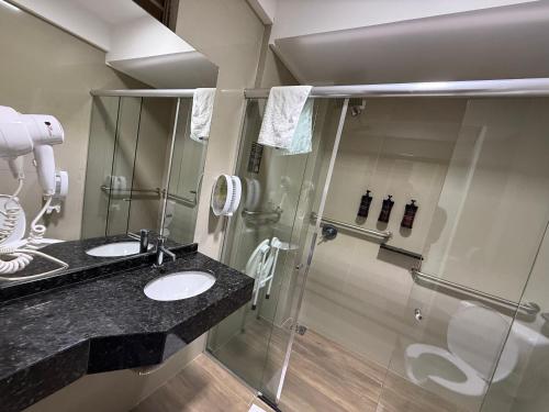 a bathroom with two sinks and a shower at Master Gold Hotel Express in Cascavel