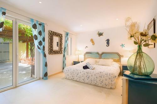 a bedroom with a bed and a vase of flowers at Les Arbousiers - Luxury Villa with 25m Pool & Sea-View Rooftop in Port Grimaud