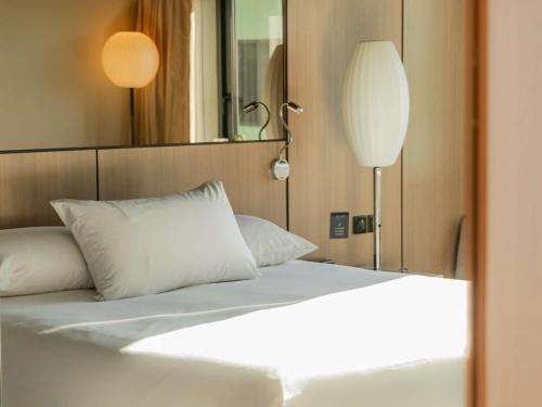 a bed with white sheets and pillows in a room at Pullman Bordeaux Lac in Bordeaux
