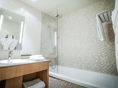 a bathroom with a tub and a sink and a shower at Pullman Bordeaux Lac in Bordeaux