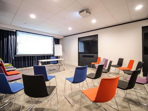 a meeting room with chairs and a projection screen at Pullman Bordeaux Lac in Bordeaux