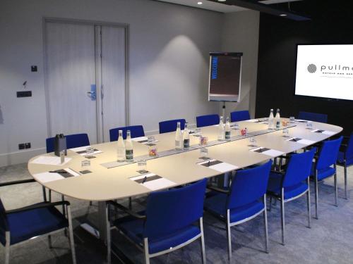 a conference room with a large table and blue chairs at Pullman Bordeaux Lac in Bordeaux