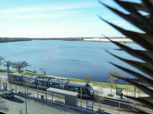 a train on tracks next to a large body of water at Pullman Bordeaux Lac in Bordeaux