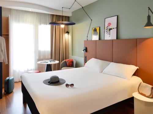 a hotel room with a bed with a hat and sunglasses at ibis Macon Sud Crêches in Crêches-sur-Saône