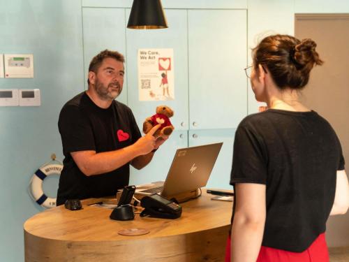 a man holding a teddy bear in front of a woman at Hotel ibis Narbonne in Narbonne