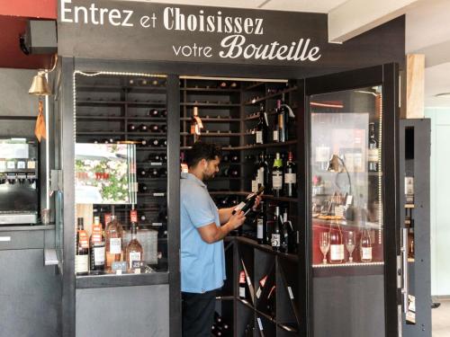 a man is standing behind a wine bar at Hotel ibis Narbonne in Narbonne