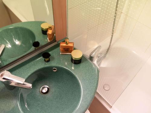 a bathroom with a green sink and a mirror at Hotel ibis Narbonne in Narbonne