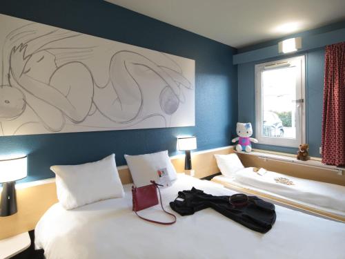 a hotel room with two beds and a large painting on the wall at Hotel ibis Narbonne in Narbonne