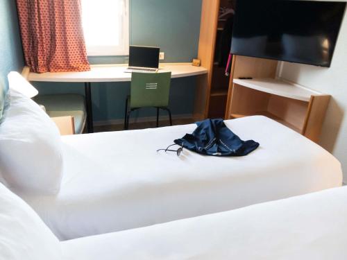 a hotel room with a bed and a laptop on a desk at Hotel ibis Narbonne in Narbonne
