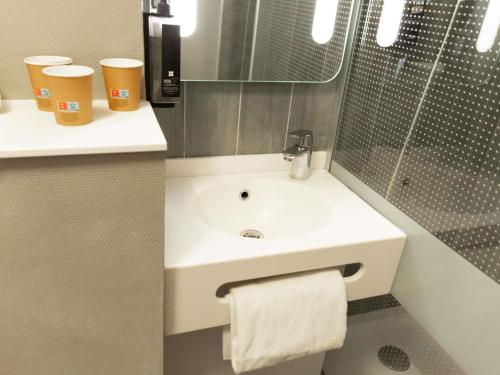 a bathroom with a white sink and a mirror at Hotel ibis Narbonne in Narbonne
