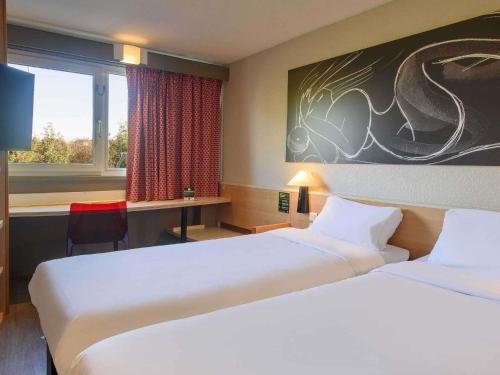 a hotel room with two beds and a desk and a window at Hotel ibis Narbonne in Narbonne