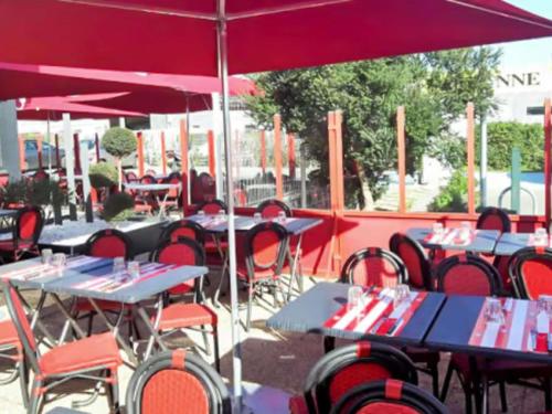 a group of tables and chairs with red umbrellas at Hotel ibis Narbonne in Narbonne
