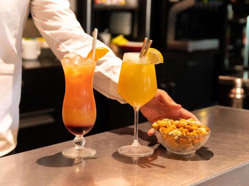 a chef is holding two drinks and a bowl of popcorn at Hotel ibis Narbonne in Narbonne