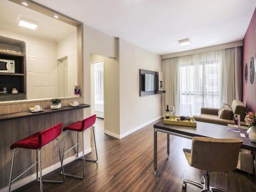 a living room with a table and red chairs at Mercure Sao Paulo Alamedas in Sao Paulo