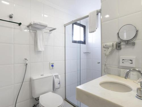 a white bathroom with a toilet and a sink at Mercure Sao Paulo Alamedas in Sao Paulo