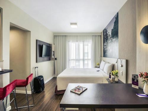 a hotel room with a large bed and a table at Mercure Sao Paulo Alamedas in Sao Paulo