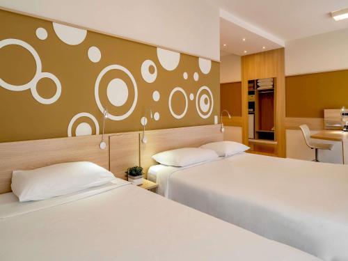 a hotel room with two beds and a desk at Mercure Sao Paulo Alamedas in Sao Paulo