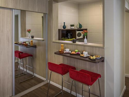 a bar in a hotel room with red bar stools at Mercure Sao Paulo Alamedas in Sao Paulo