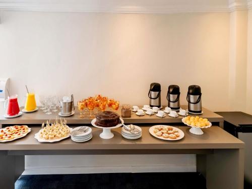 a table with plates of food and desserts on it at Mercure Sao Paulo Alamedas in Sao Paulo