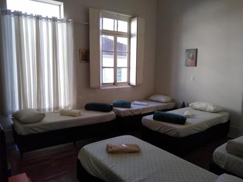 a room with four beds and a window at Pousada Divino Espírito Santo in Paraisópolis