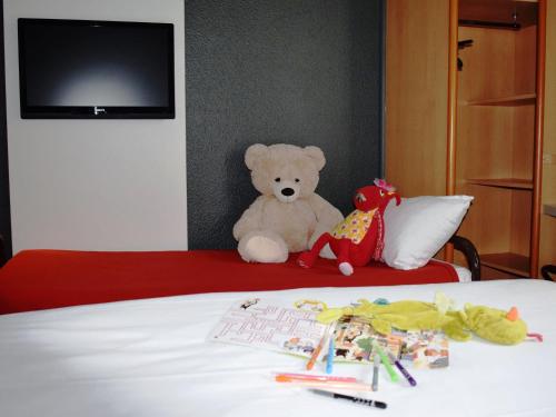 a teddy bear sitting on top of a bed at ibis Chartres Ouest Luce in Chartres