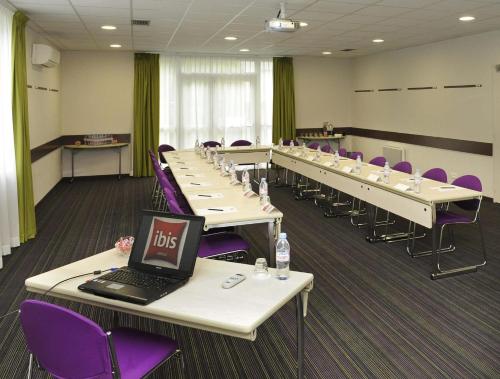 a room with rows of tables with purple chairs and a laptop at ibis Chartres Ouest Luce in Chartres