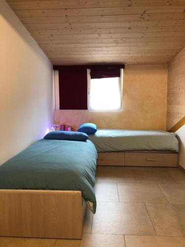 two beds in a room with a window at villa morena in Cavalese