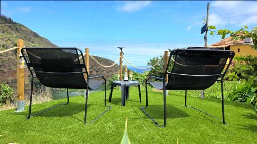 two black chairs sitting on the grass with a swing at The North Paradise - Porto Moniz in Porto Moniz