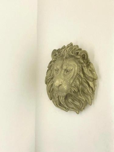 a bronze lion head on a white wall at Couzy entire home 20 min from international Airport in Luanda