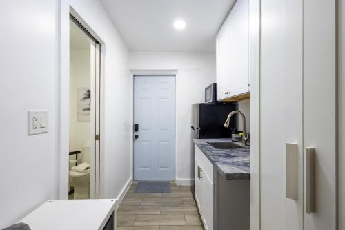 a kitchen with white cabinets and a sink and a door at The Side Villa in Miami