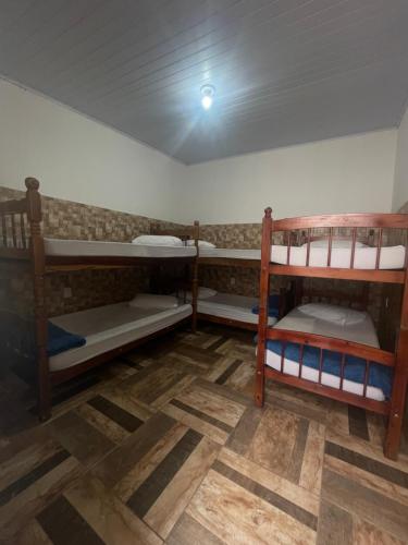 ein Zimmer mit drei Etagenbetten in einem Zimmer in der Unterkunft Pousada Três Marias Cachoeira Paulista in Cachoeira Paulista