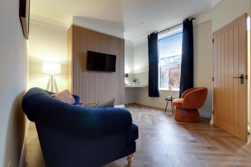 a living room with a blue couch and a window at Luxury 2 Bed House in Lindley Huddersfield 2 mins from HRI 5 mins from Town Centre and M62 in Lindley