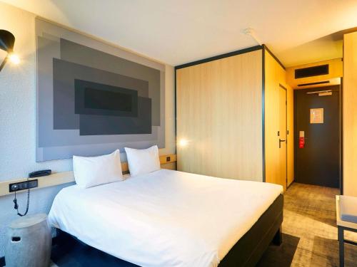 a bedroom with a large white bed in a room at ibis Le Mans Est Pontlieue in Le Mans